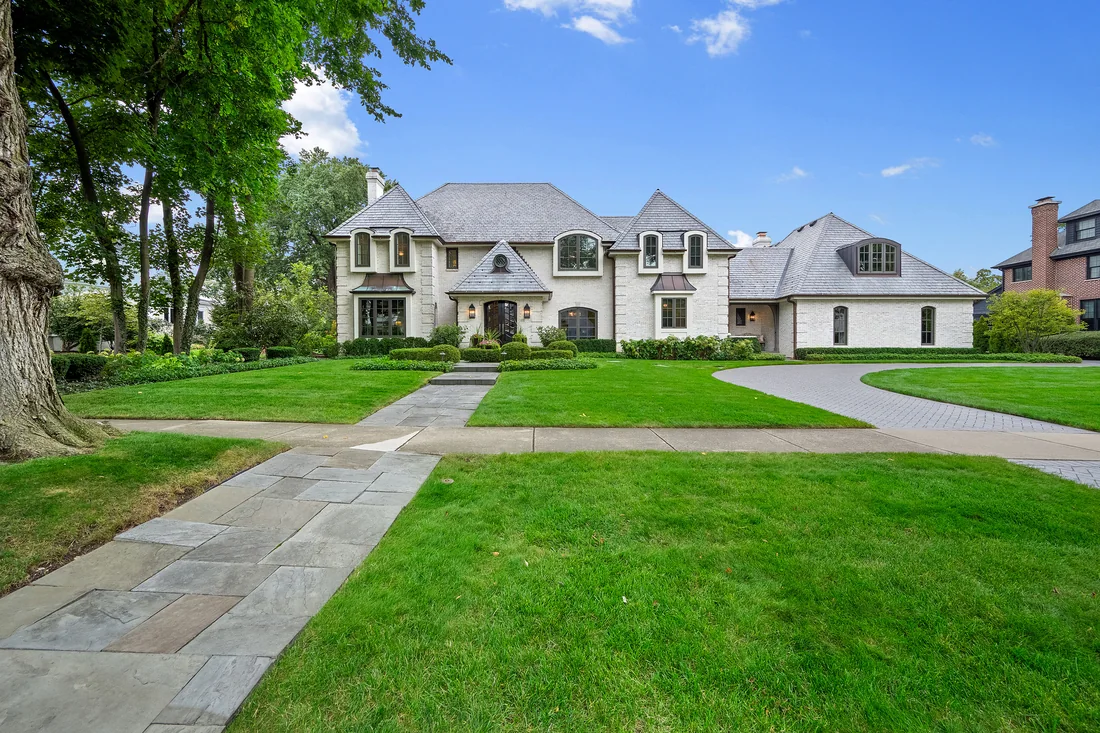 Large residence with a stone facade, landscaped lawn and curved driveway