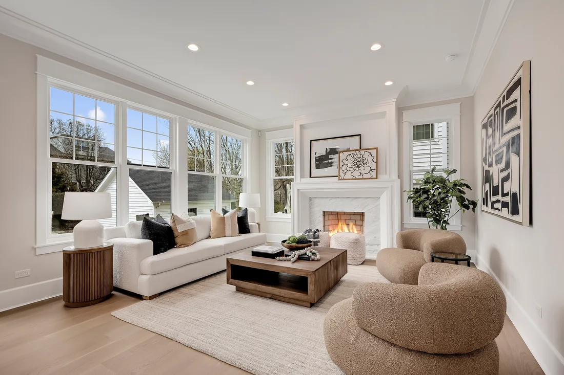 Neutral living room with curved armchairs, a fireplace and garden windows
