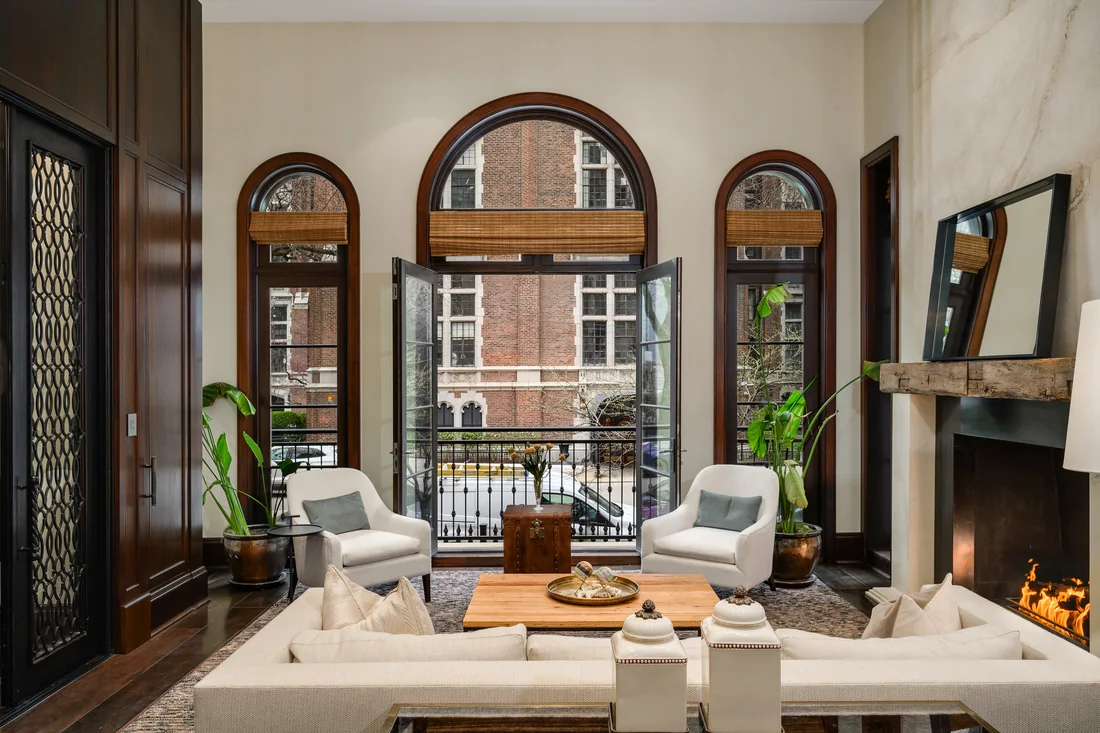 Tall arched windows above a living room with a fireplace and cream seating