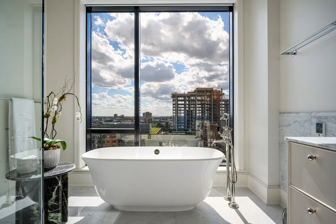 Freestanding bathtub beside a floor-to-ceiling window overlooking the city