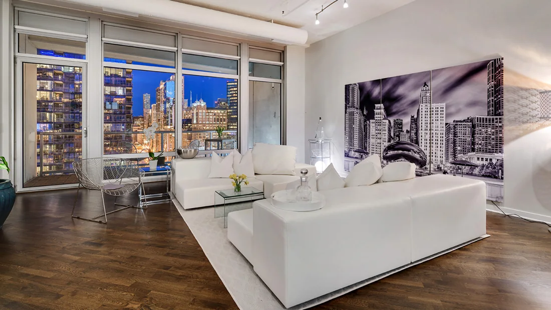 White living room overlooking the illuminated Chicago skyline