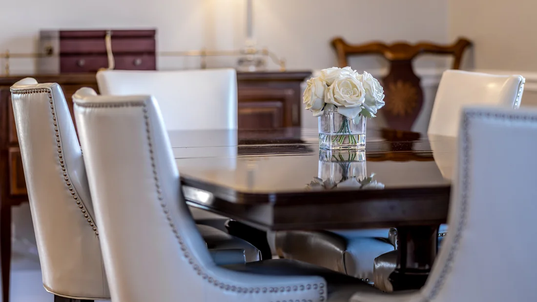 Close view of upholstered dining chairs and flowers on a polished table