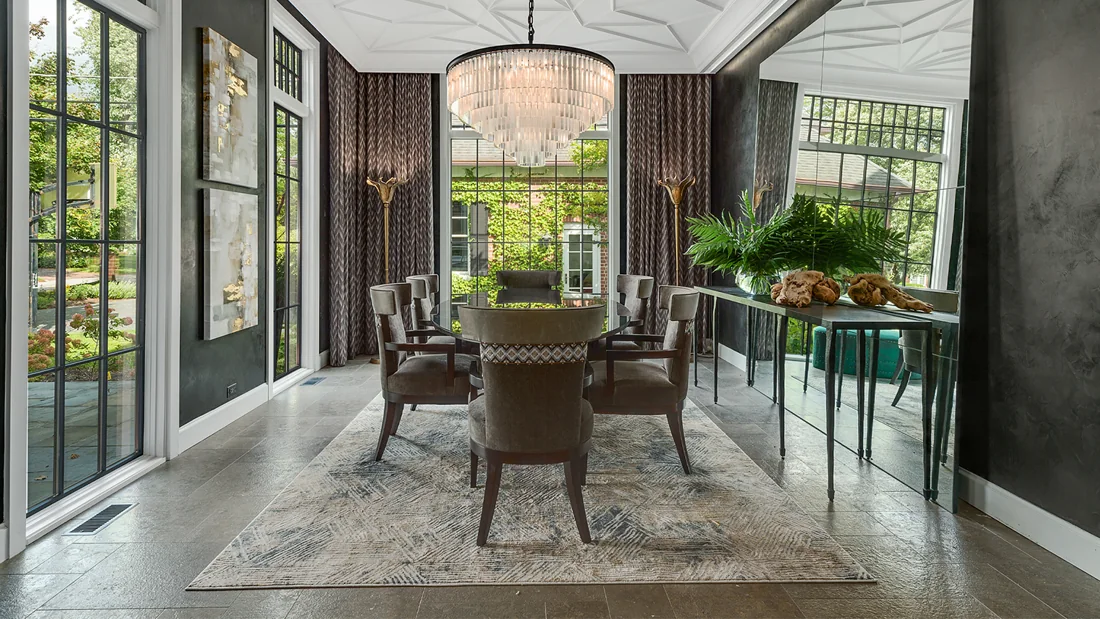 Dining room enclosed by tall windows looking onto a green garden