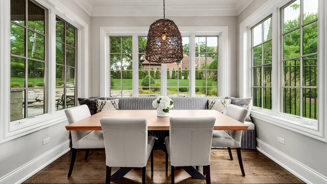 Bright breakfast room with wicker pendant light and leafy views